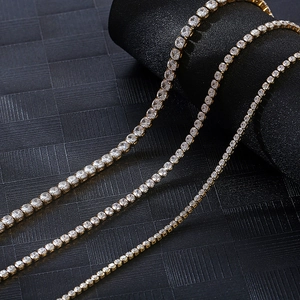 Close-up of three sparkling 18K gold-plated tennis chains with zircon stones on dark base