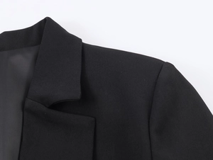 Close-up of black peplum blazer featuring lapel collar and detailed fabric texture