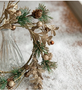 Gros plan d'aiguilles de pin de Noël dorées avec pommes de pin et paillettes sur neige