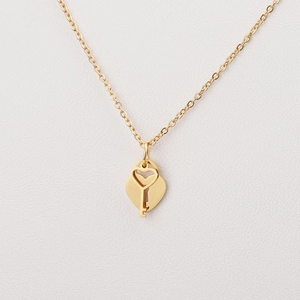 Macro detail of gold stainless steel heart locket and key pendant with polished finish
