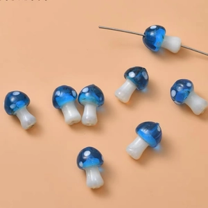 Detailed view of blue glass mushroom beads for DIY jewelry making with white spots