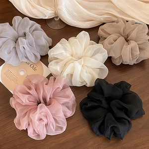 Flat lay of five organza scrunchies in grey, beige, brown, pink, and black colors