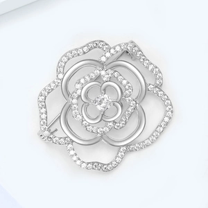Macro detail of silver floral brooch with hollow petals and micro-inlaid cubic zirconia