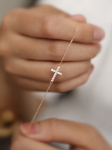 Close-up of gold-plated silver cross bracelet featuring sparkling zircon stones detail
