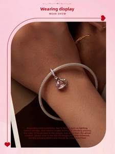 Close-up of silver mesh bracelet with hollow heart charm and pink pear-shaped gemstone