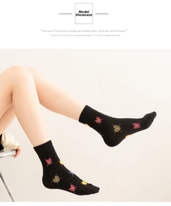 Detailed knit of black mid-calf socks with colorful retro heart patterns and ribbed cuffs