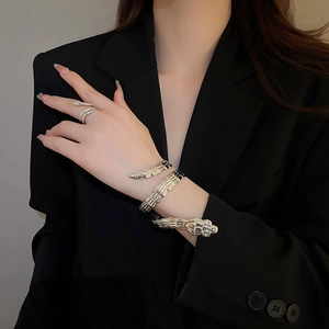 Detailed close-up of punk style silver snake bone bracelet set on a black blazer background