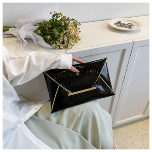 Close-up of black crocodile pattern envelope clutch with elegant gold metal trim detail