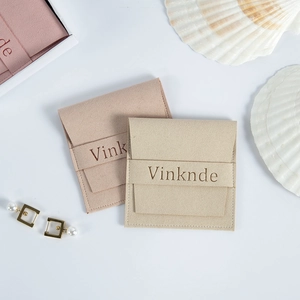 Gros plan de pochettes bijoux en daim avec fermeture bouton et boucles d'oreilles perles