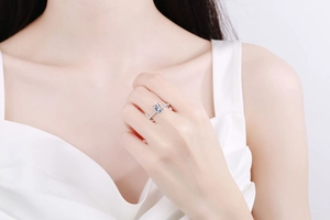 On-hand display of a 1-carat emerald cut moissanite ring with a silver micro-pave band