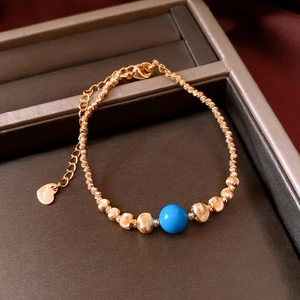 Vue détaillée du bracelet perlé plaqué or 18 carats avec une pierre ronde bleue centrale
