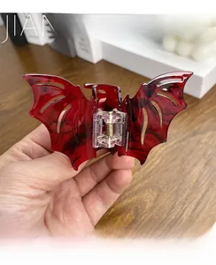 Detailed view of gothic bat-shaped hair claw with red and black marble texture