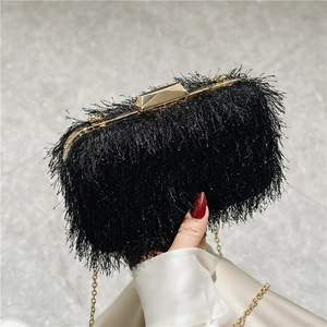 Detail of elegant black tassel evening bag with gold metal frame and chain strap