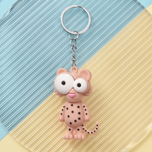 Close-up of a cute pink cheetah PVC keychain with large eyes on a textured background