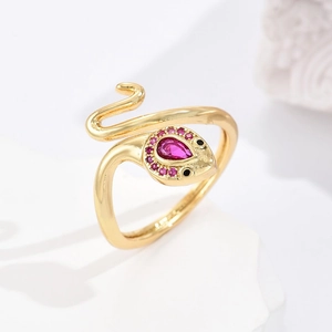 Gold snake ring with pink drop-shaped gemstone and crystal pavé on white marble base