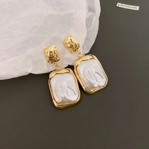 Gros plan de boucles d'oreilles dorées vintage avec nacre sur une base grise texturée