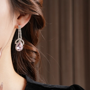 Close-up of luxury silver drop earring with pink pear-cut gem on model's ear