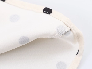 Gros plan détaillé du tissu en coton à pois montrant les coutures de l'ourlet nettes