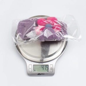 Digital scale showing the weight of a purple knitted baby turban with large flower detail