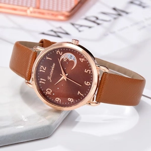 Macro view of rose gold watch case with moon phase dial and brown leather texture strap