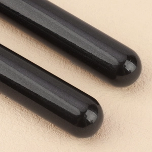 Macro shot of black makeup brush handles with glossy pearlescent finish and rounded ends