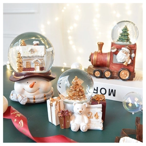 Close-up of vintage Christmas snow globes with resin figurines on a festive table