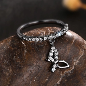 Macro shot of gun-black butterfly pendant ring with zircon pavé on a textured stone