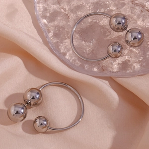 Detailed close-up of silver beaded hoop earrings resting on soft pink satin and glass