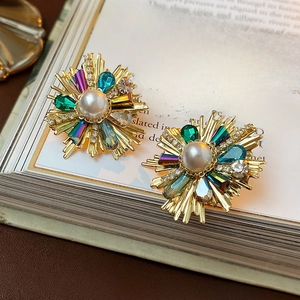 Detail of vintage flower stud earrings with pearl and colorful crystals on a book
