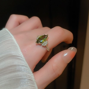 Detail of 14K gold plated marquise green emerald ring with zircon accents on finger