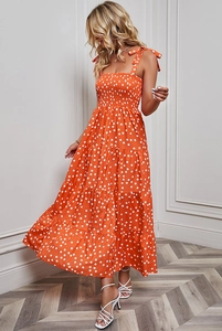 Detail of orange polka dot sundress featuring tied shoulder straps and smocked bodice