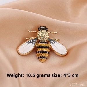 Detail shot of a bee brooch with rhinestones and white enamel wings, 4*3cm size