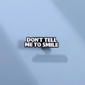 Enamel lapel pin with 'DON'T TELL ME TO SMILE' text on minimalist gradient background