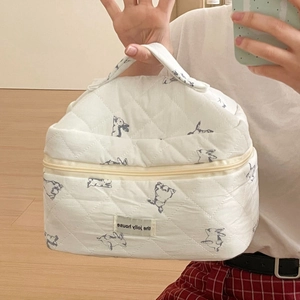 Detail of white quilted cosmetic bag with rabbit patterns and a top handle