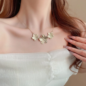 Vintage style golden flower necklace with three metallic petals on a female model
