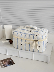 Detail of quilted makeup bag with blue stripes, star patterns and ribbon zipper pull