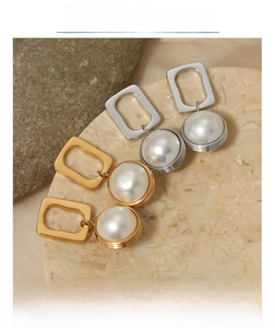 Macro detail of geometric pearl drop earrings in gold and silver finish on marble