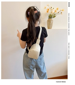 Kids minimalist beige chest bag with adjustable strap worn on the back of a child