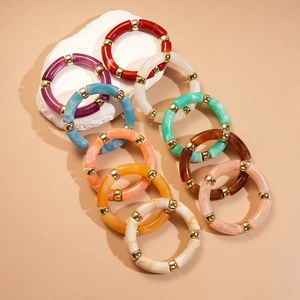 Bracelets géométriques en acrylique multicolore avec perles dorées sur fond beige