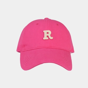Dettaglio del cappellino rosa acceso con toppa beige della lettera R e trama in twill