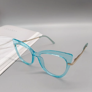 Dettaglio della montura cat-eye verde acqua con aste in metallo dorato su sfondo grigio