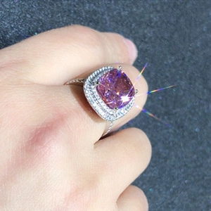 Close-up of cushion cut pink zircon ring with double halo setting on a female hand
