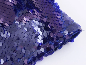 Macro di paillettes blu scintillanti su tessuto per abiti da sera con riflessi