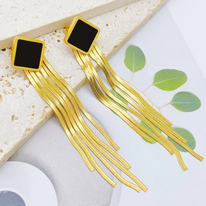 Detail of square black studs with long gold snake chain tassels on marble surface