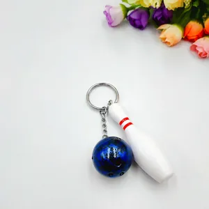 Miniature blue marble bowling ball and white pin keychain set on a clean white background