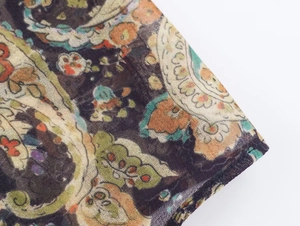 Gros plan sur le tissu à motif paisley avec des détails orange et verts vibrants