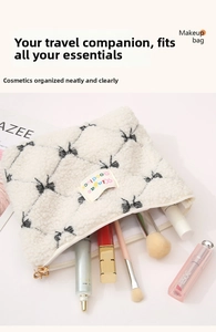Detail of plush faux shearling makeup bag featuring black bow print and gold zipper