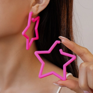 Gros plan de boucles d'oreilles étoiles en acrylique rose fluo portées sur l'oreille