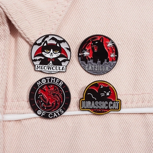 Close-up of four parody cartoon cat enamel pins displayed on pink fabric background