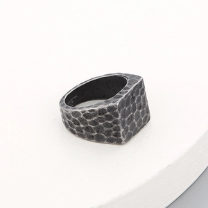 Macro detail of men's wide vintage stainless steel ring with hammered texture finish